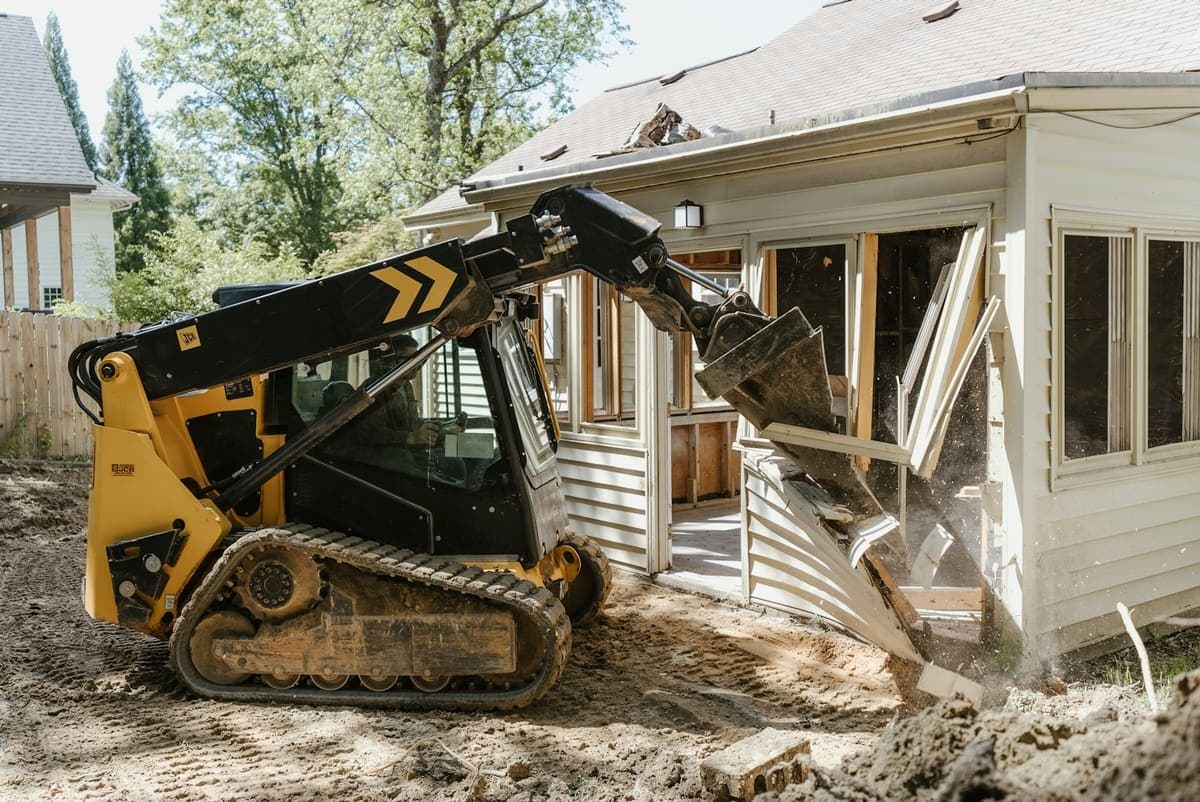 Compact track loader demolishing a residential structure