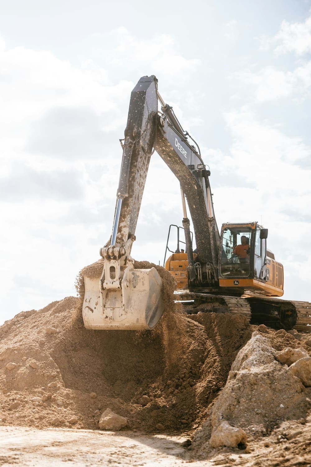 Excavator operator working a dirt pile on a job site
